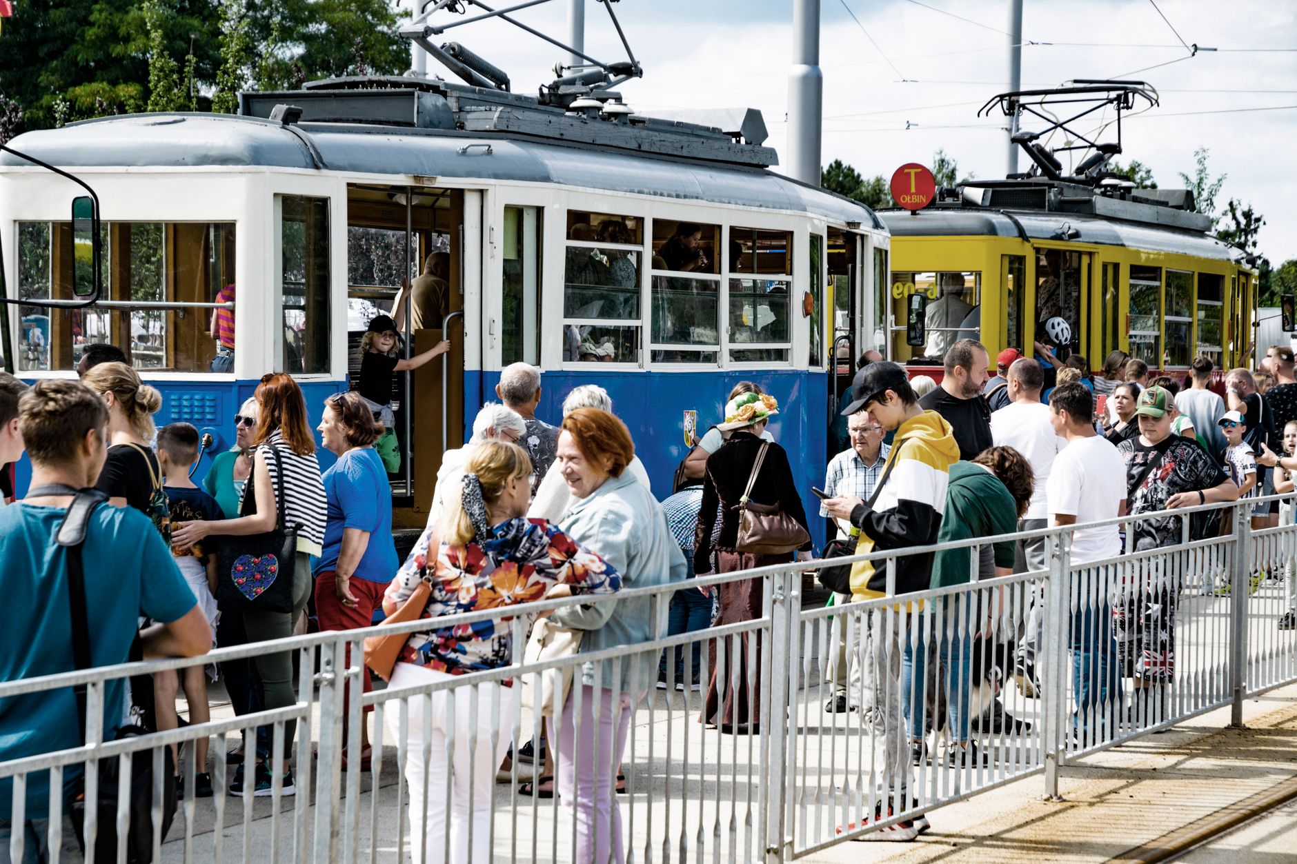 Busy tram stop in Wrocław with people boarding vintage and modern trams.