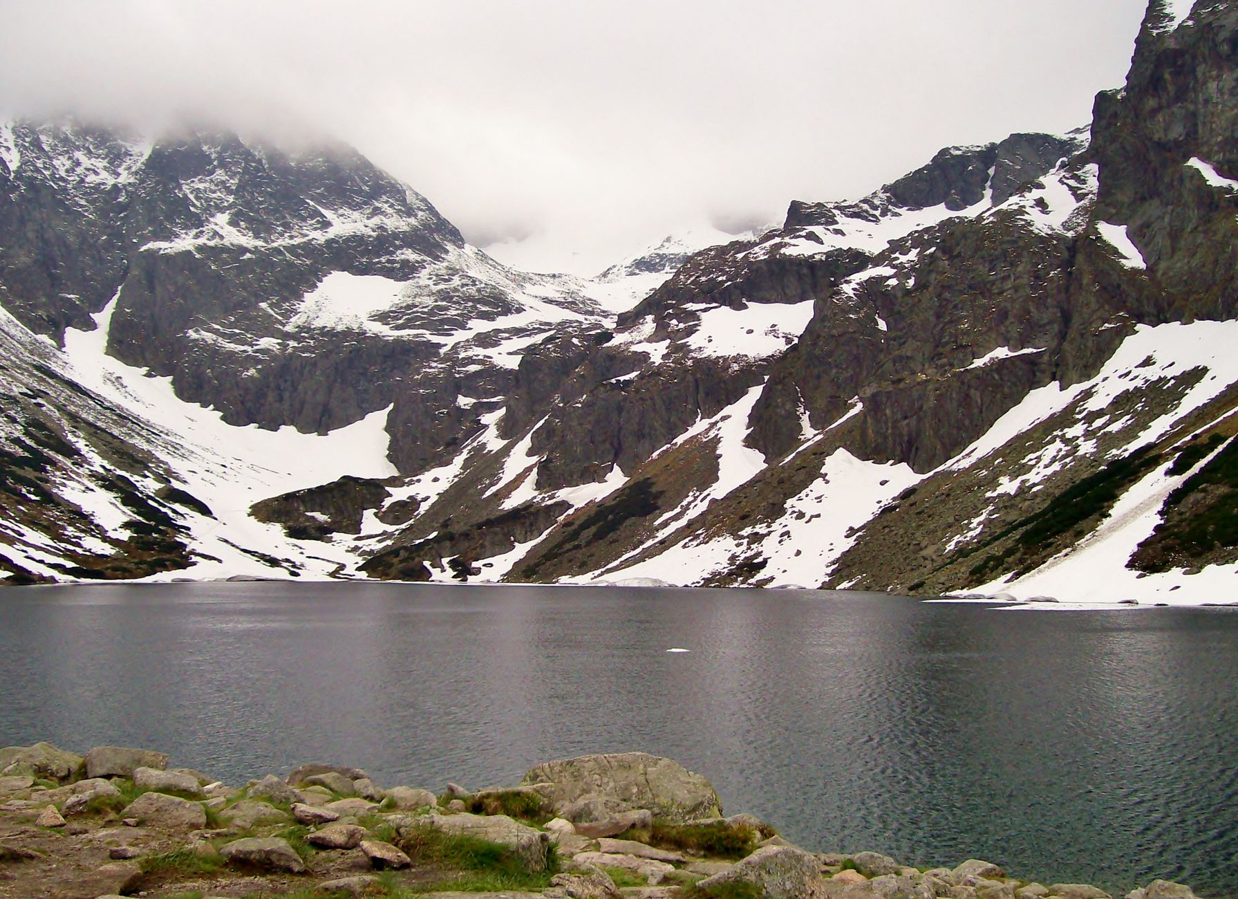 Beautiful view of snow-covered Tatra Mountains and tranquil lake in Poland, perfect winter landscape.