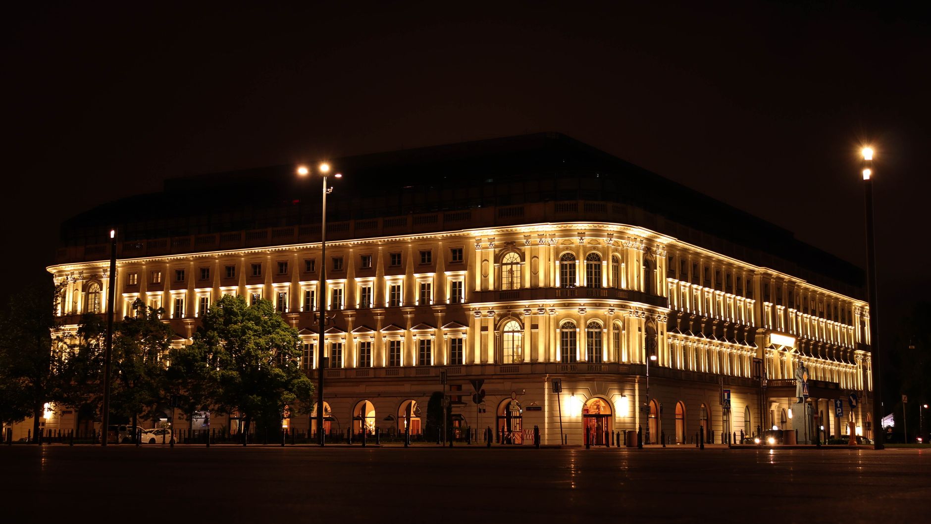 A well-lit view of Raffles Europejski, a landmark in Warsaw, Poland.