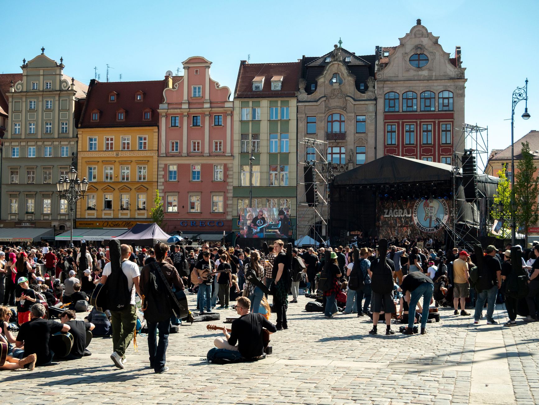 Crowd enjoying an outdoor music festival in Wrocław, Poland, with colorful historic buildings.