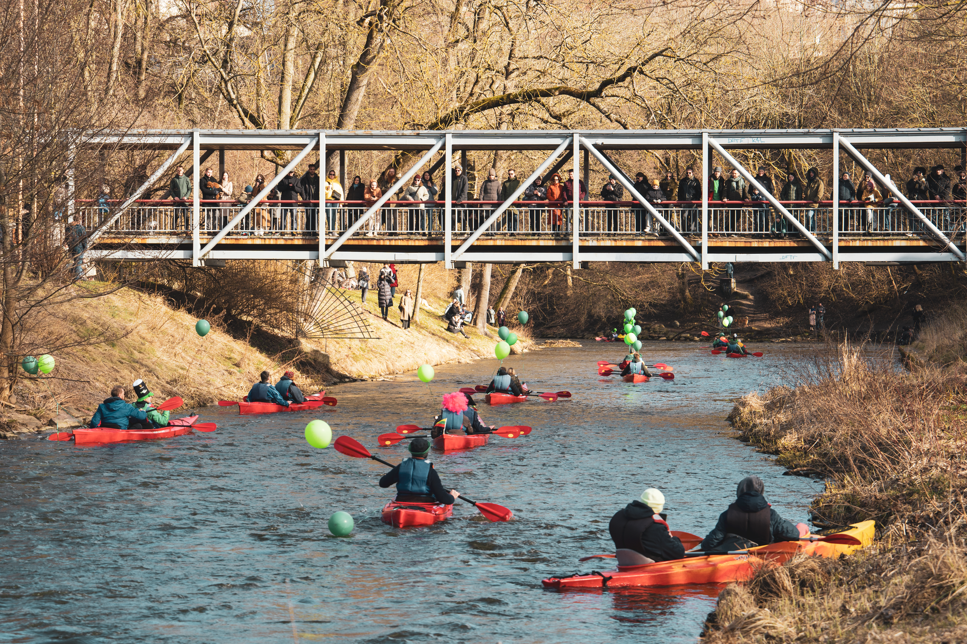 Kayakers paddle under a bridge in Vilnius, Lithuania as spectators watch, during a spring festival.