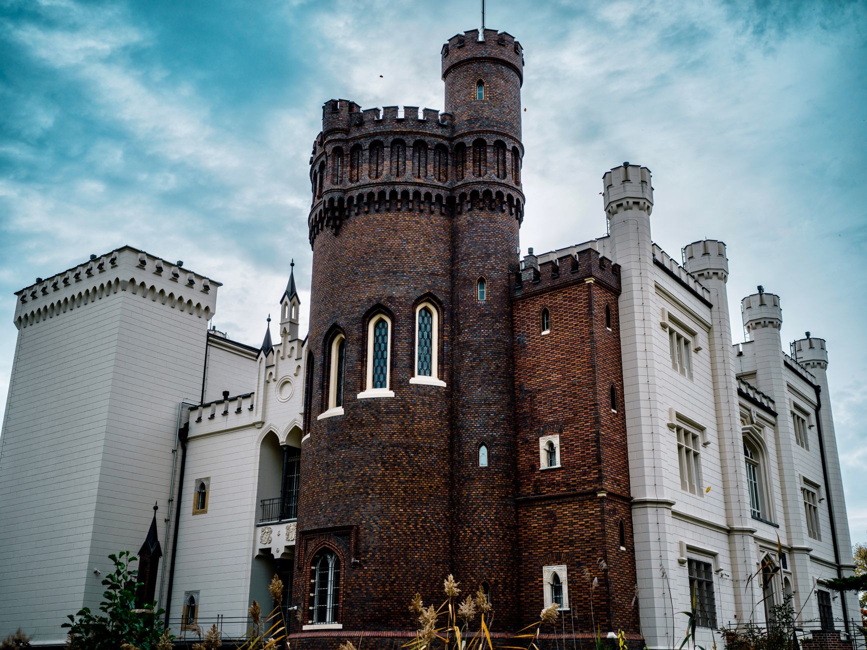 Stunning exterior of Kórnik Castle showcasing gothic revival architecture under blue skies.