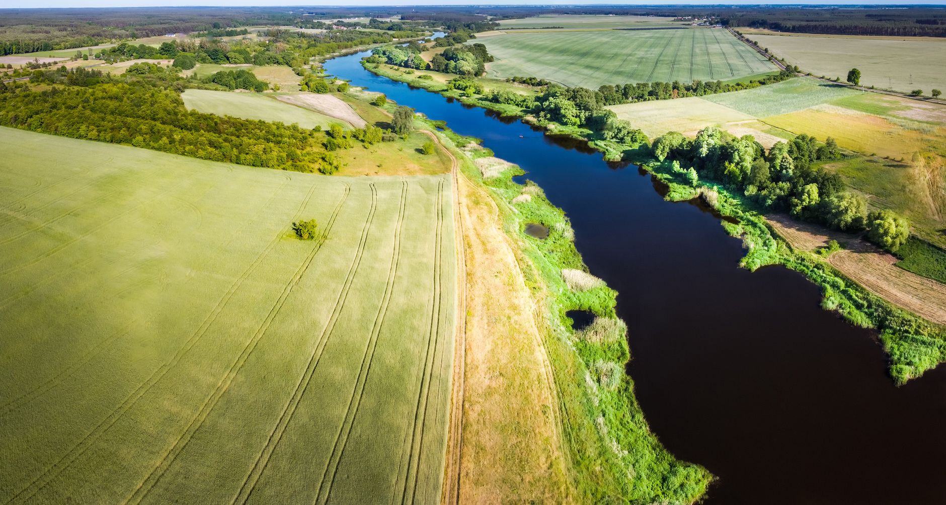 Beautiful drone shot of the Warta River with surrounding lush countryside fields in Poland.