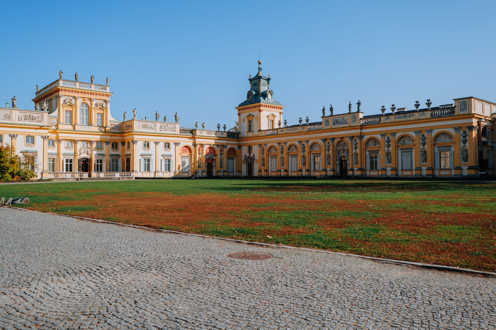 Stunning view of Wilanów Palace in Warsaw, showcasing Baroque architecture under a clear blue sky.