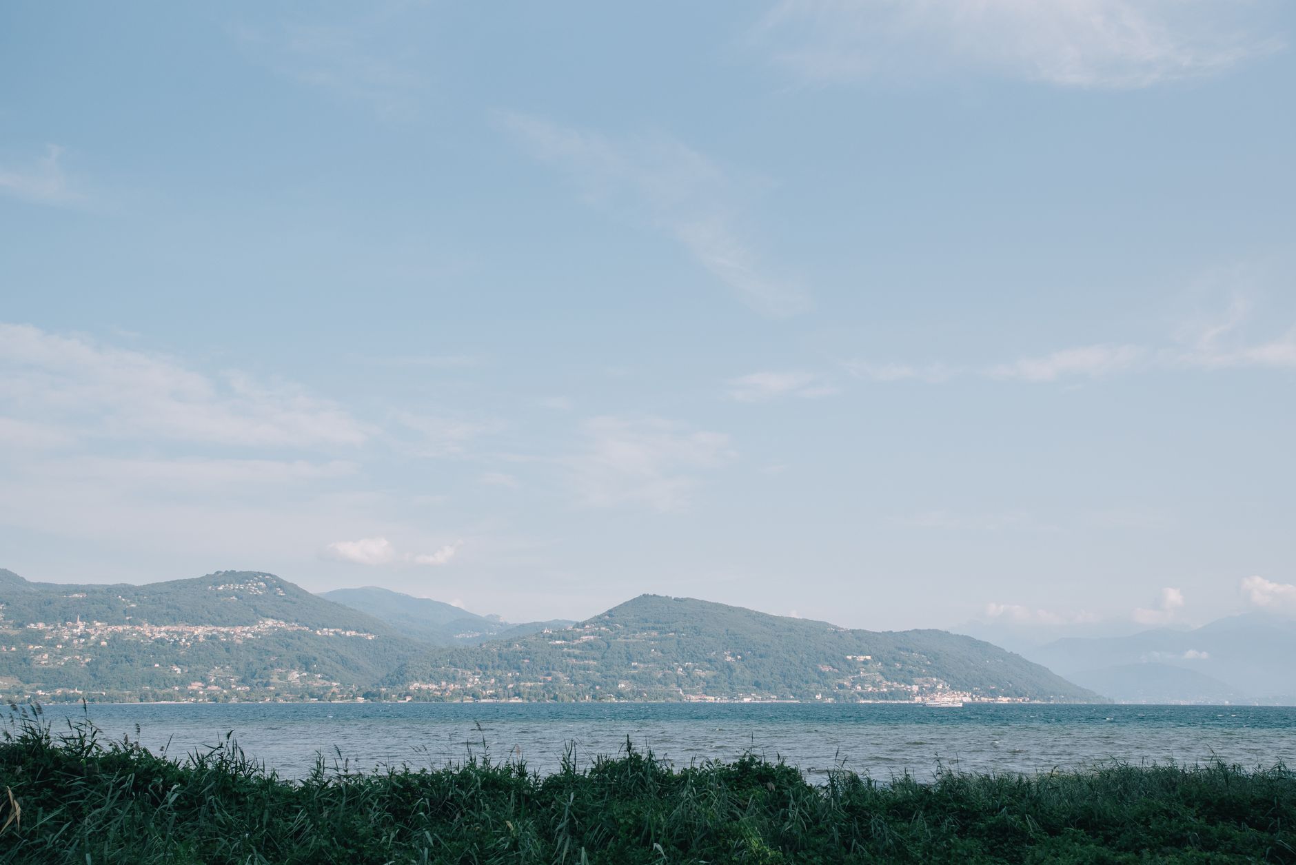 Breathtaking landscape of Lake Como with distant mountains under a blue sky.