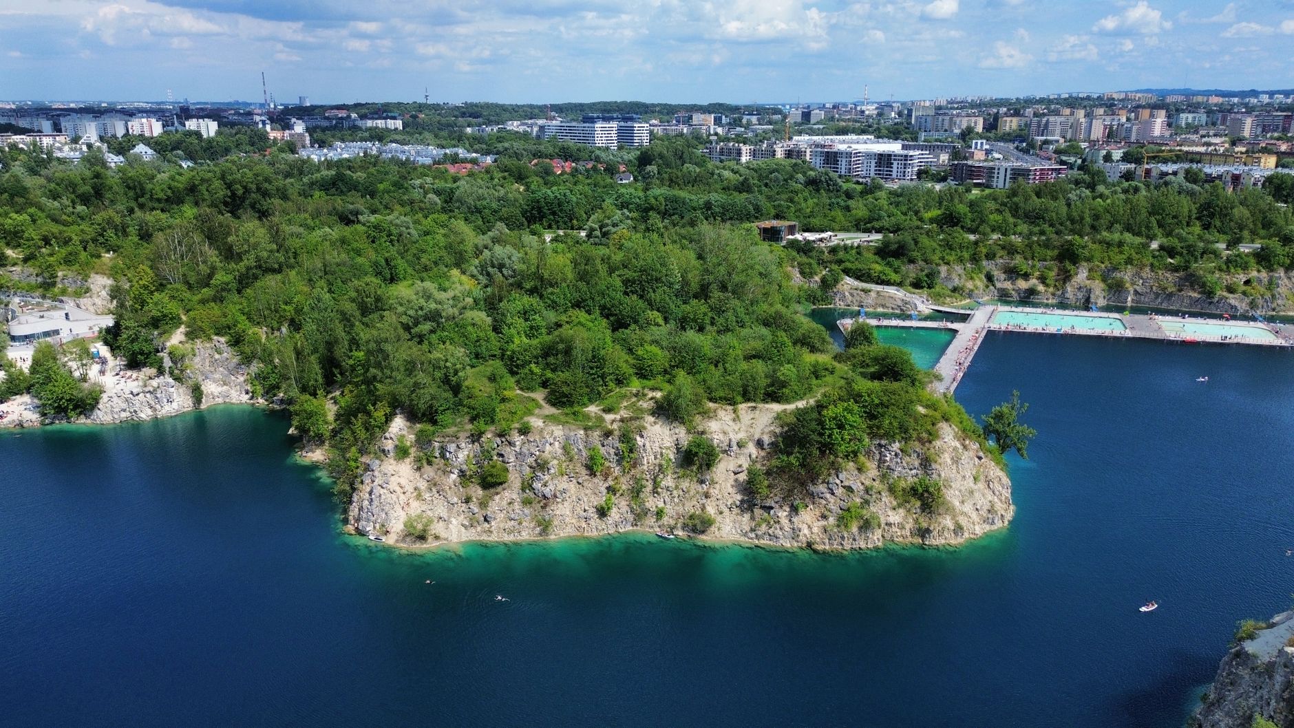 Aerial view of Zakrzówek Quarry in Krakow, showcasing lush greenery and turquoise waters.