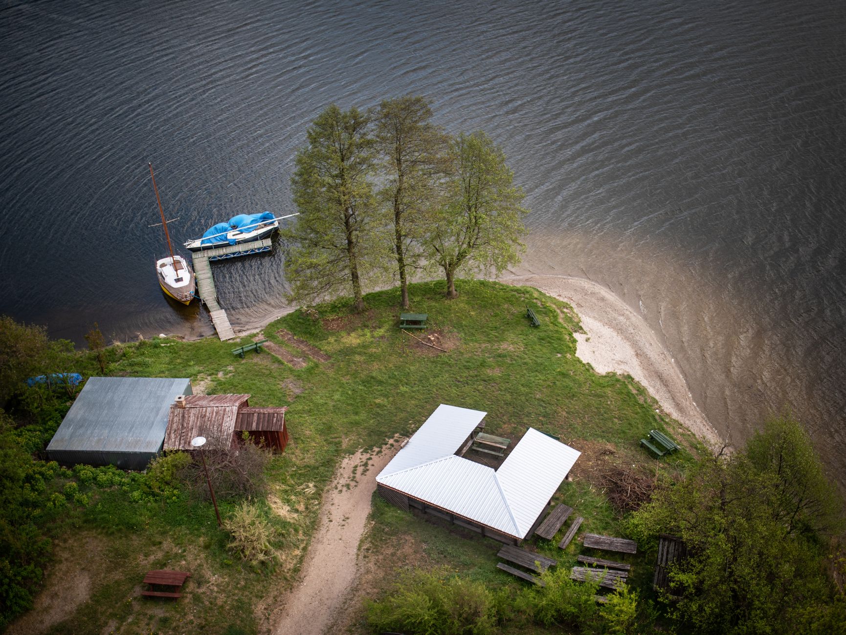 Aerial shot of a lakeside area with boats and picnic benches in Wdzydze Kiszewskie, Poland.