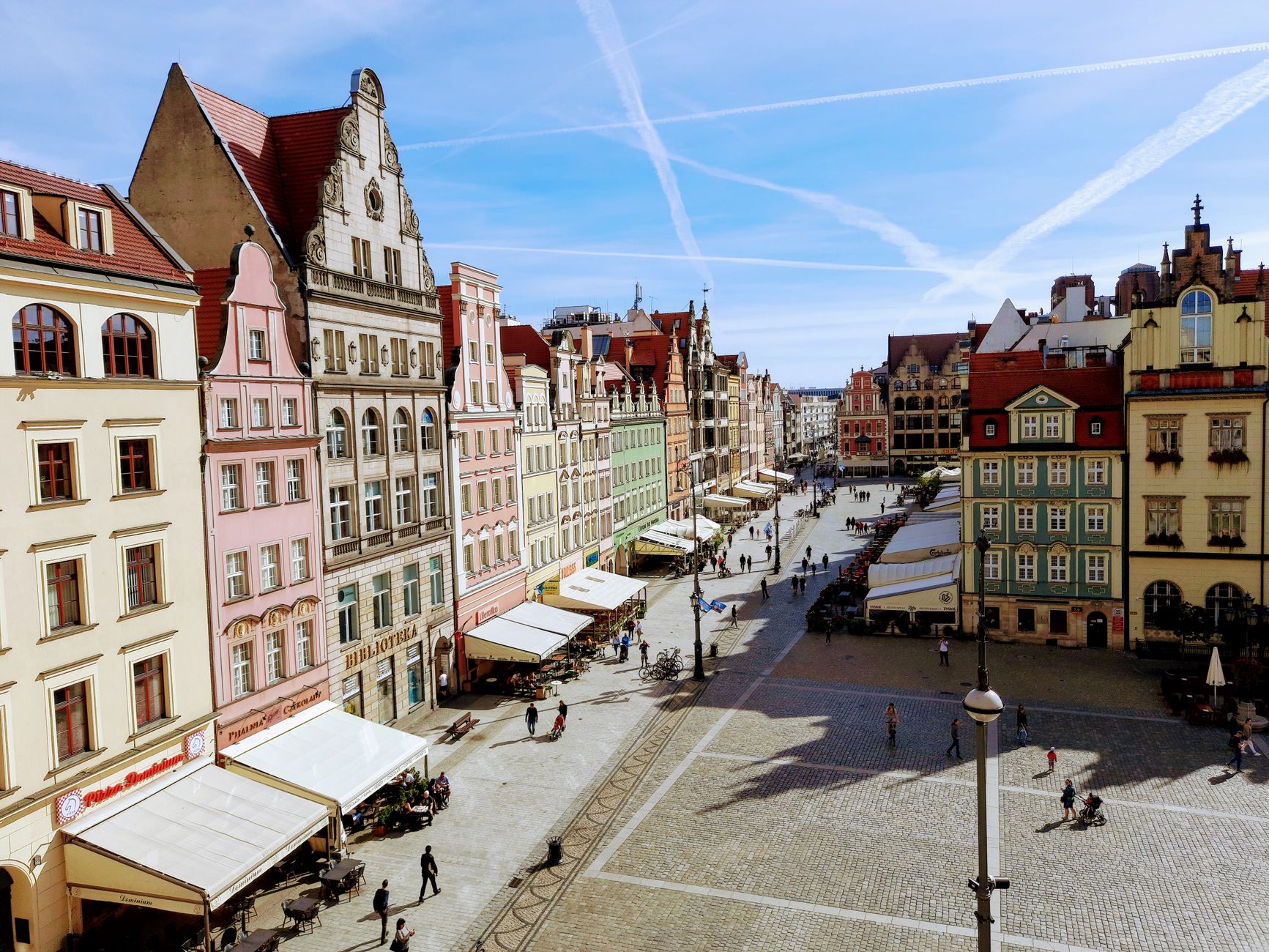 Explore the colorful historic facades and lively atmosphere of Wrocław's Market Square on a sunny day.