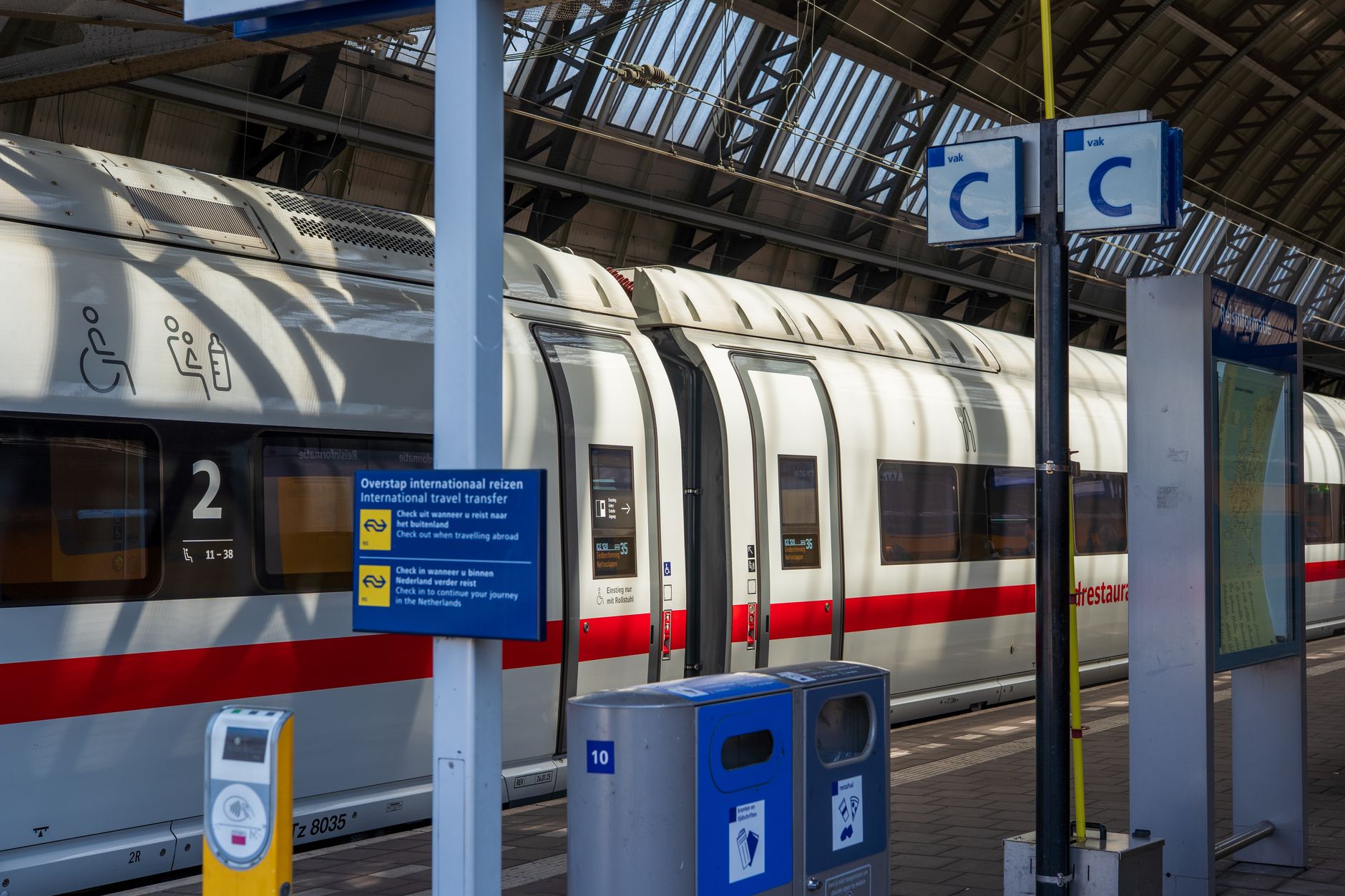 A modern passenger train at Amsterdam station, highlighting international travel signage.