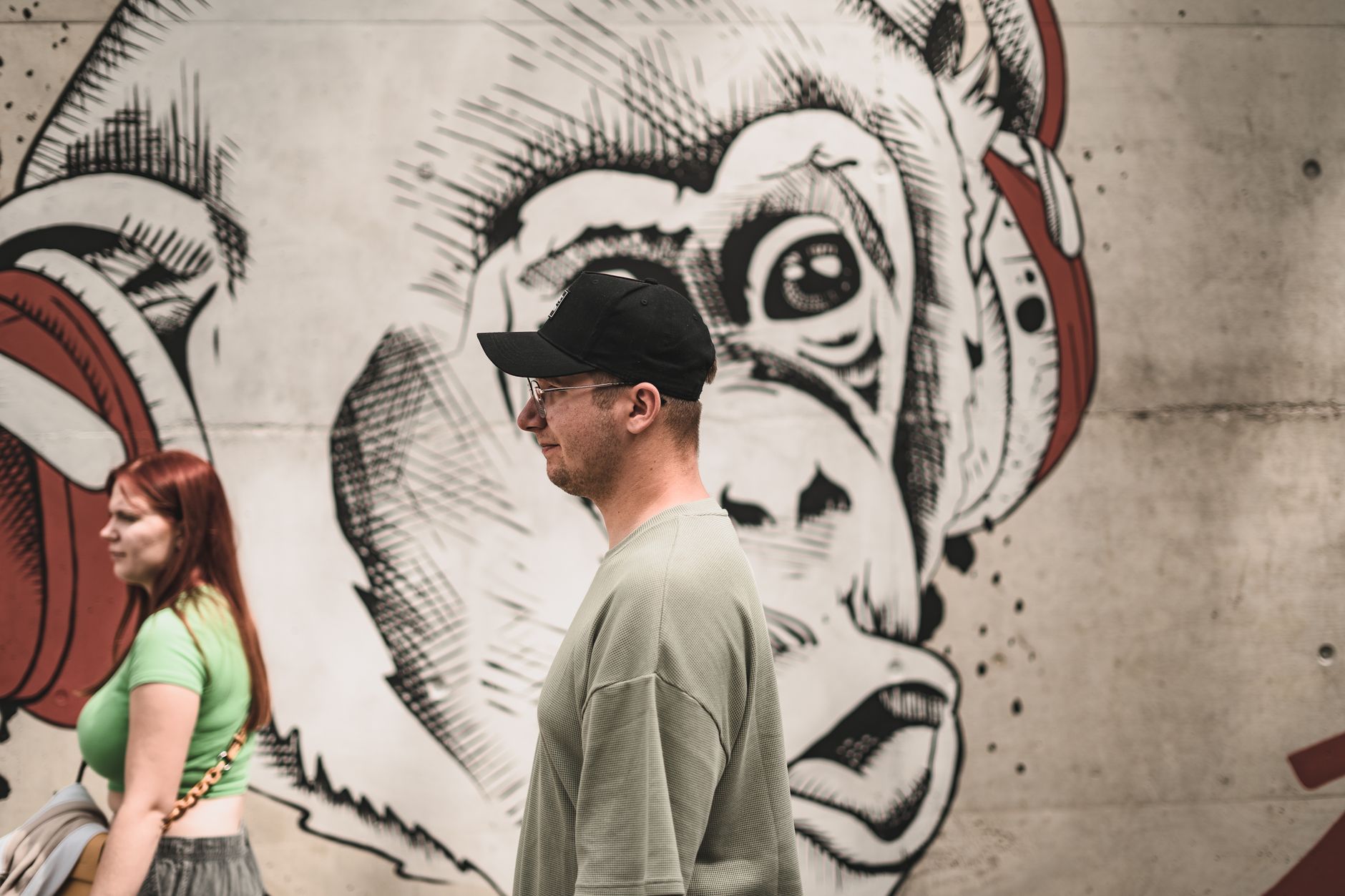 Men and women walking by a street art mural in Łódź, Poland. Urban and artistic vibe.
