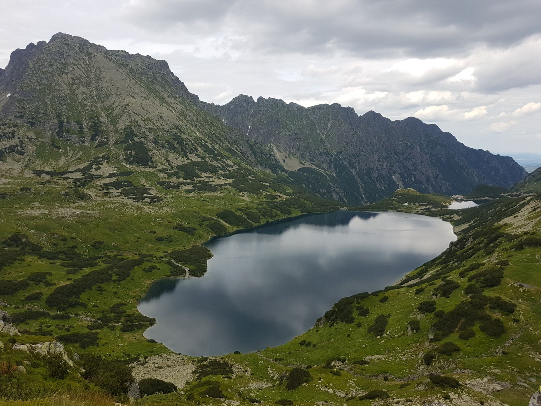 Breathtaking view of Wielki Staw in the Tatra Mountains, Lesser Poland, surrounded by lush greenery.