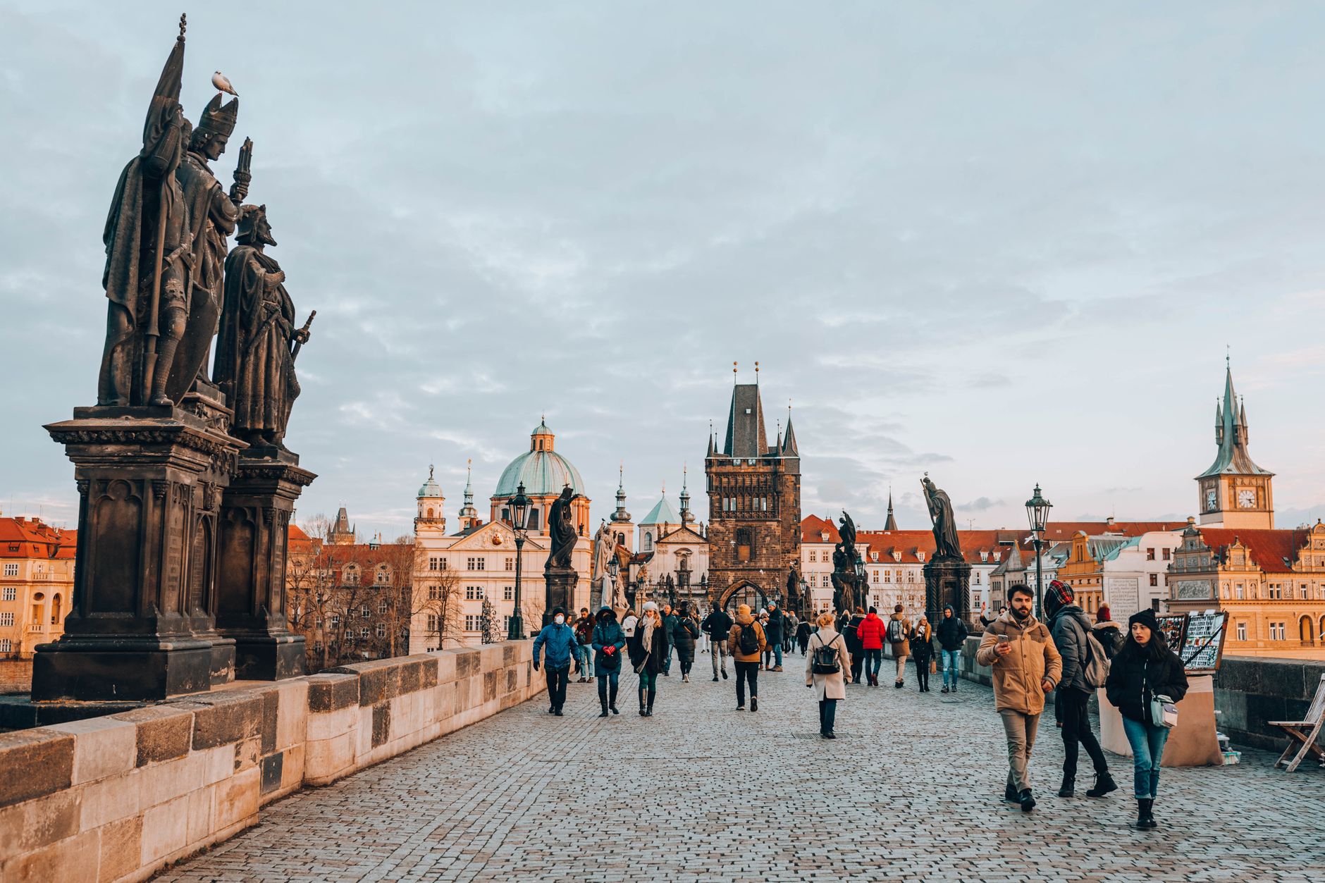 Capture of the lively Charles Bridge in Prague, featuring statues and historic architecture.