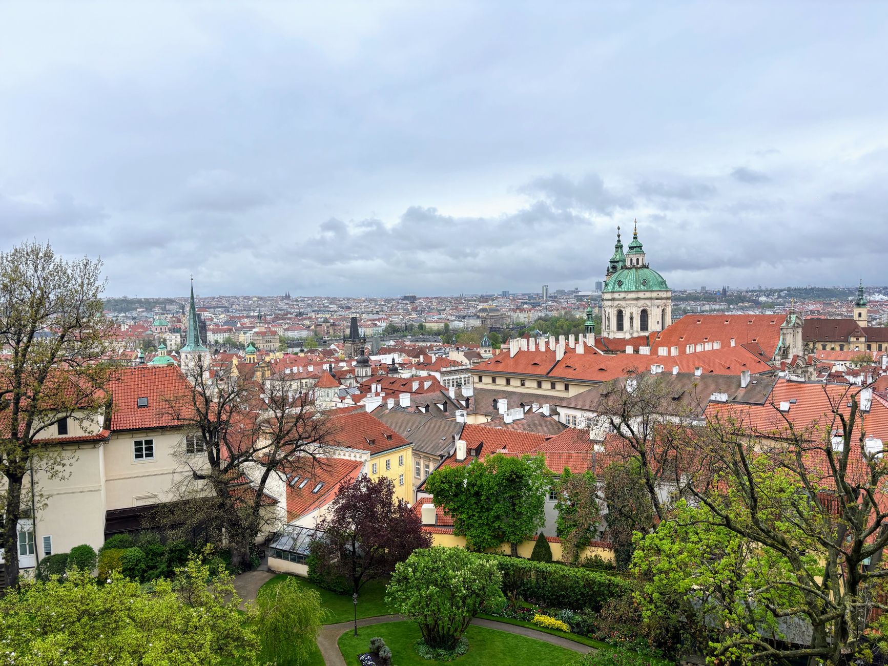 Panoramic view of Prague's old town with iconic red roofs and green dome. Captivating urban landscape.