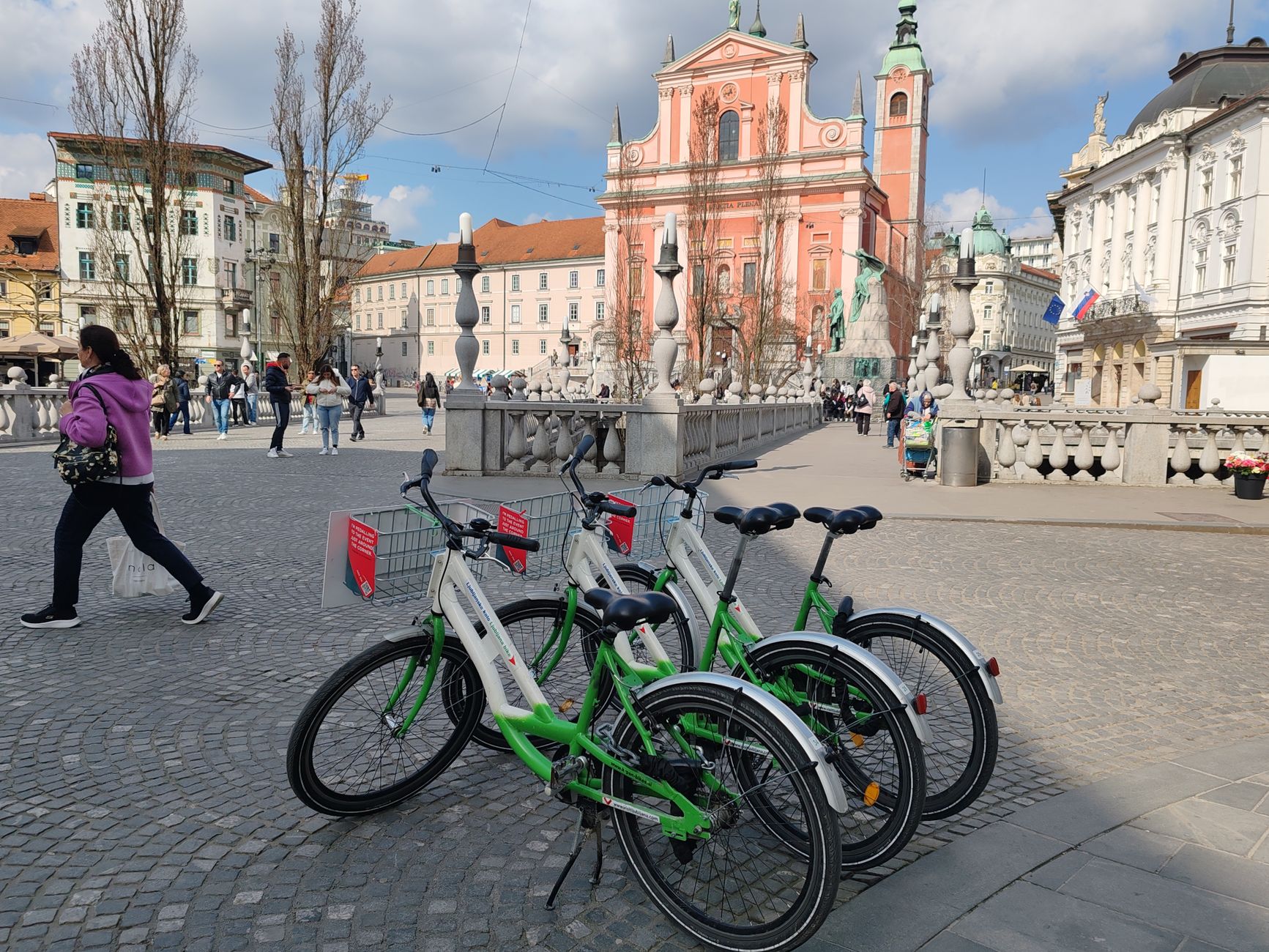 Green rental bicycles on a Ljubljana plaza with urban architecture.