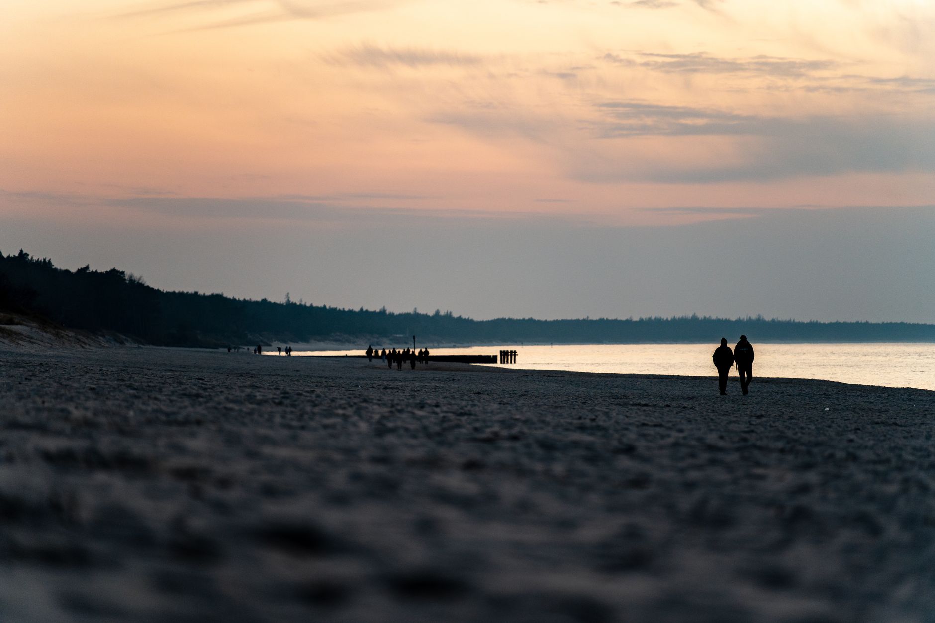 A serene sunset view of a couple walking on Kołobrzeg beach, Poland.