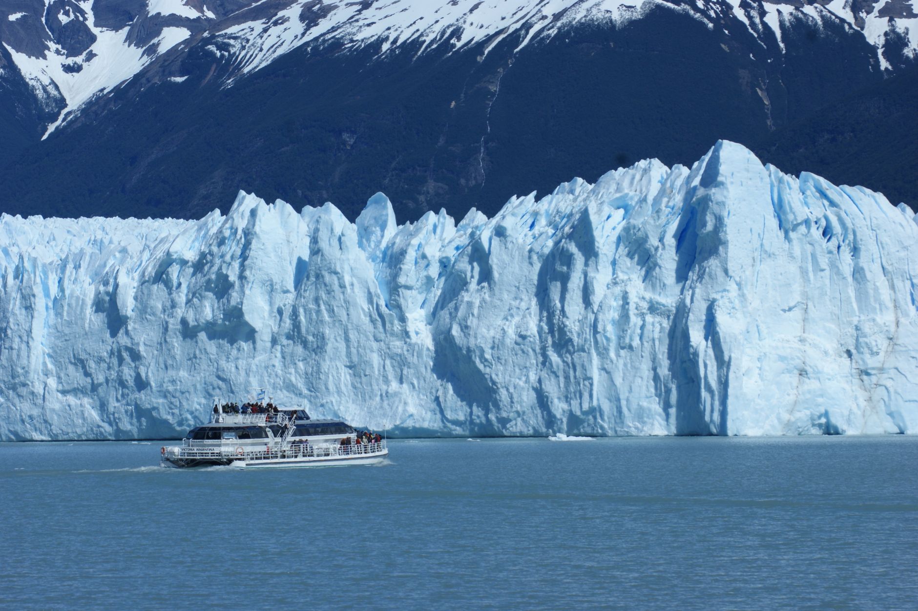 A tour boat cruises past the majestic Perito Moreno Glacier in Argentina, showcasing nature's icy wonders.