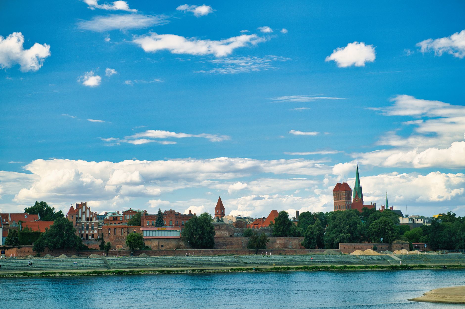 Beautiful cityscape of Toruń Old Town with historic architecture and river in the foreground.