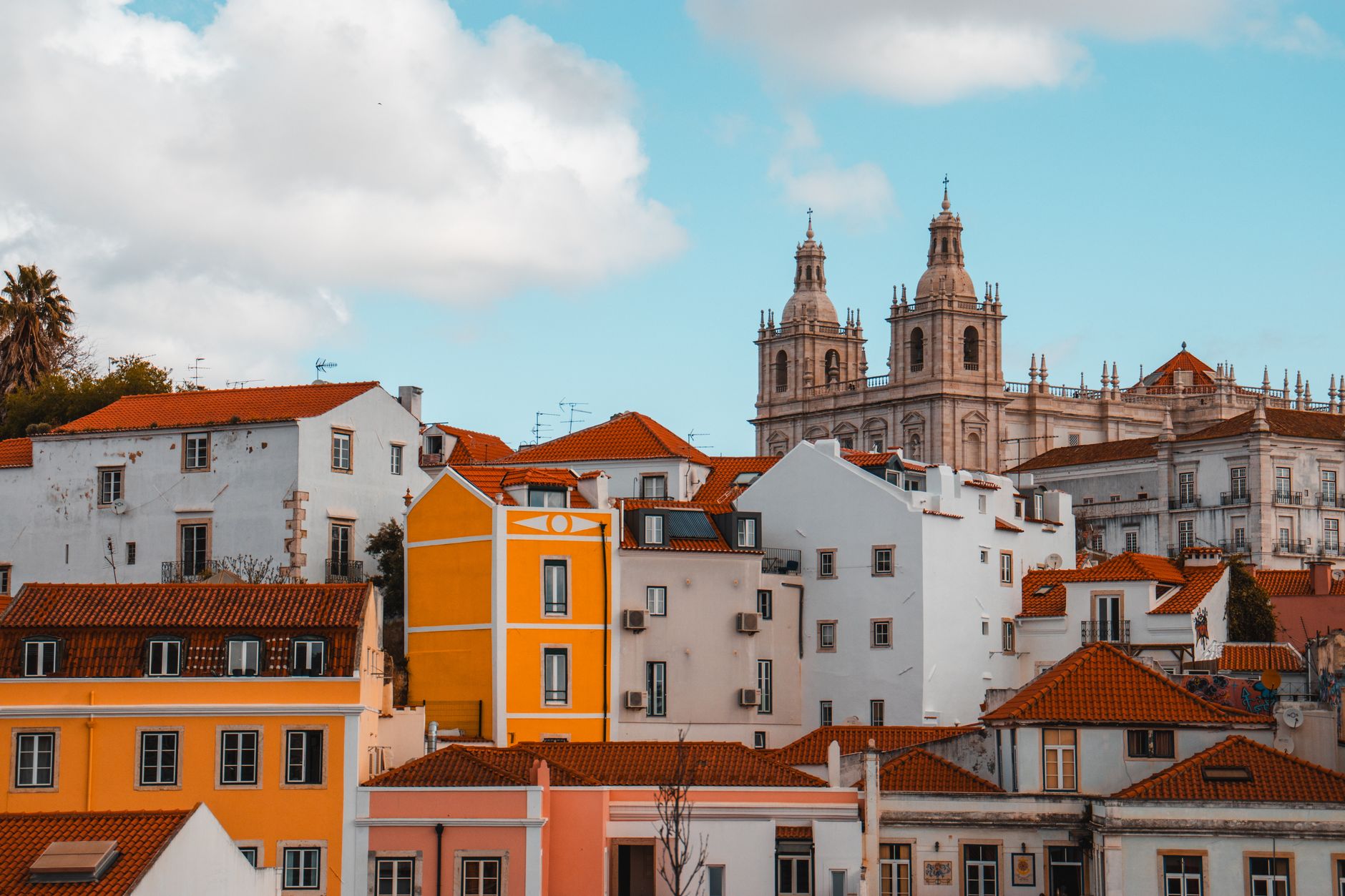 Scenic view of colorful Lisbon rooftops with church towers under blue skies.