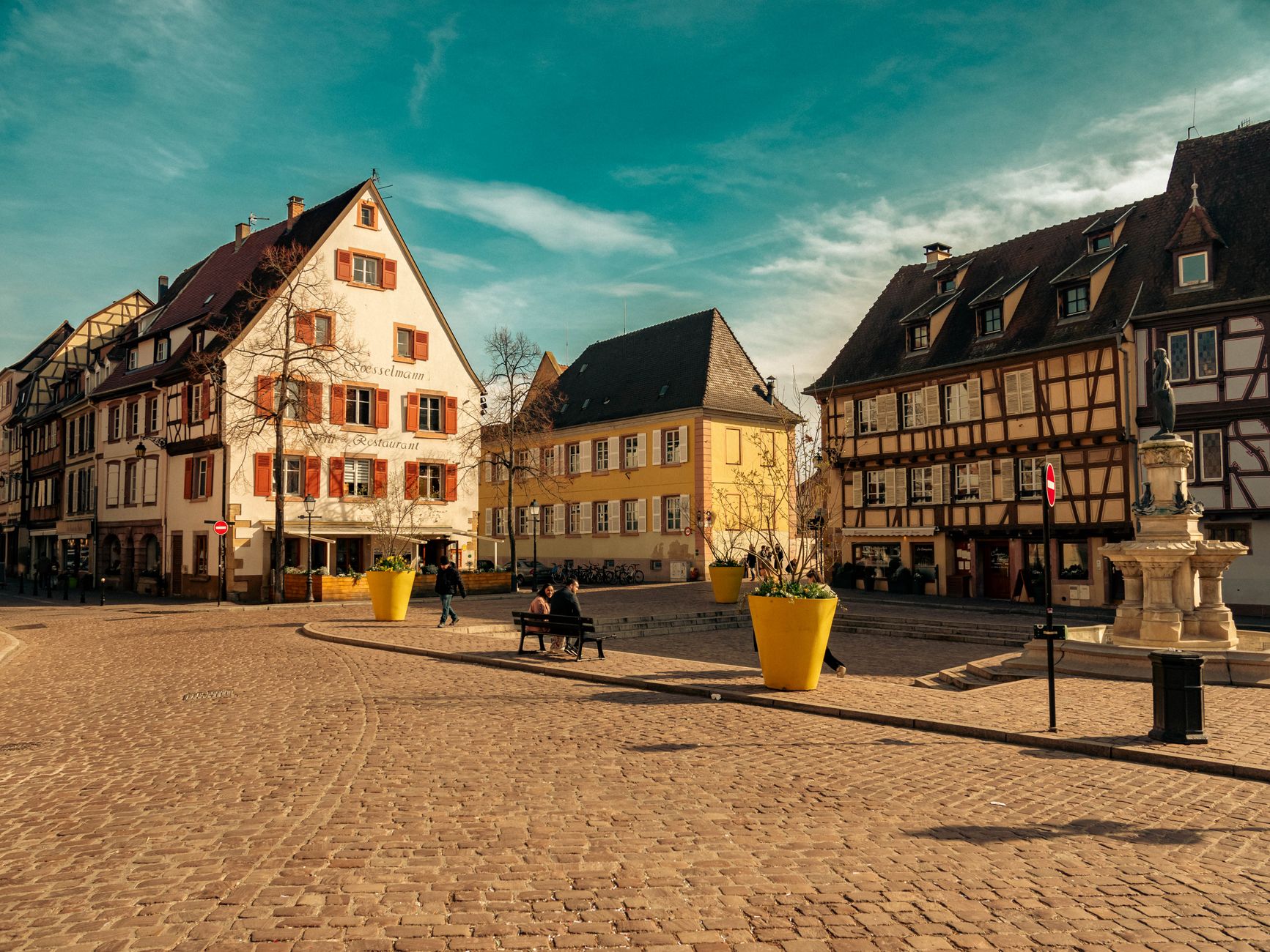 Picturesque view of Colmar's old town square featuring historic timber-framed houses and a quaint cobblestone street.