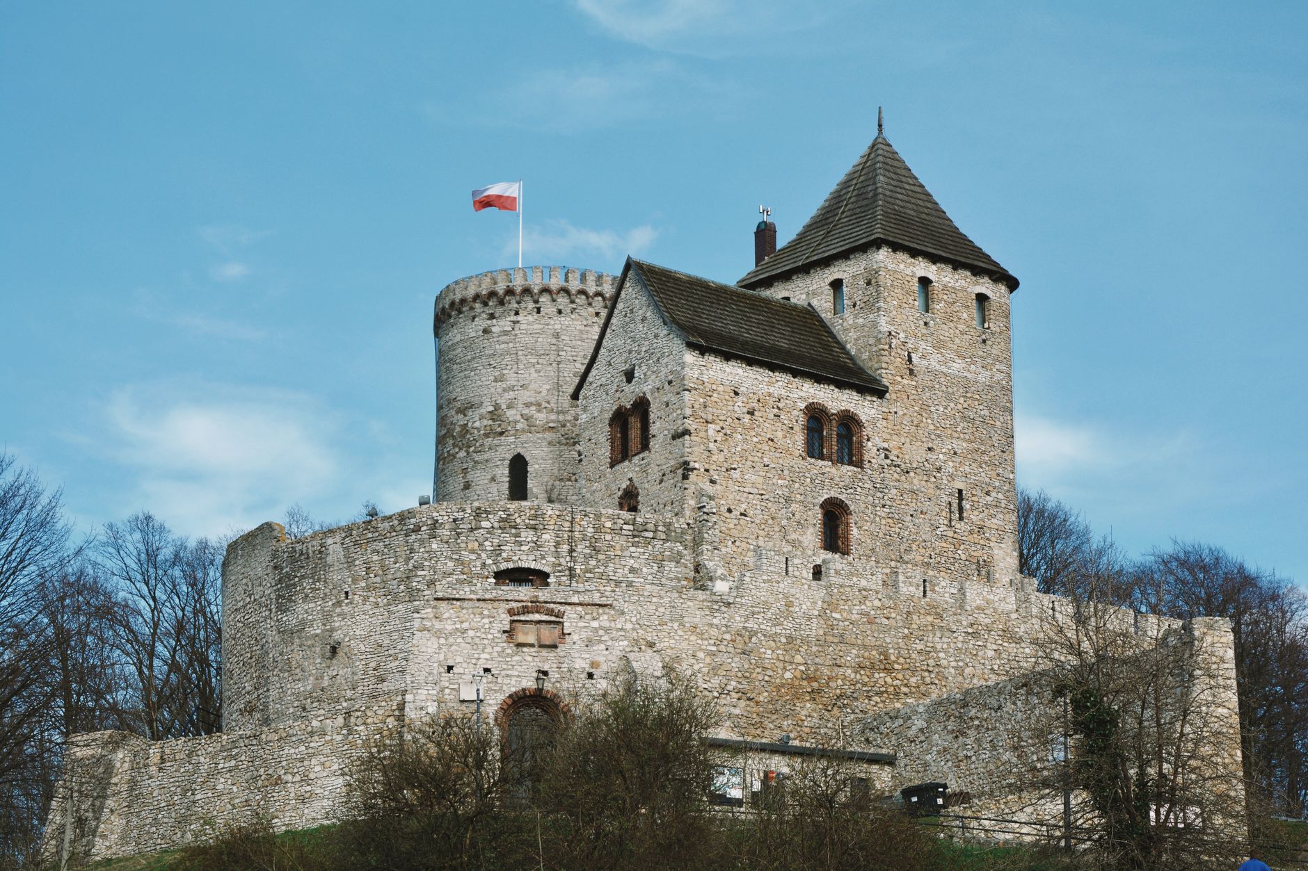 View of the medieval Będzin Castle in Poland, showcasing its historical architecture under a clear blue sky.