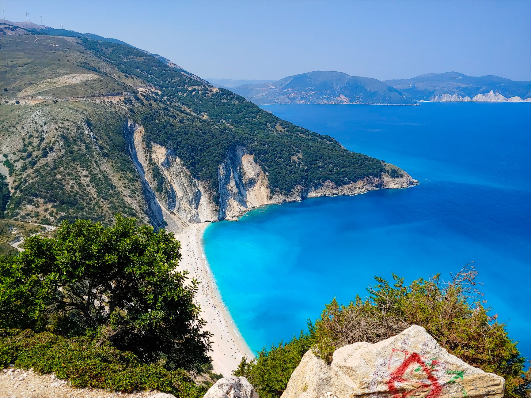 Stunning aerial view of Myrtos Beach with turquoise waters and rugged cliffs on Kefalonia Island, Greece.