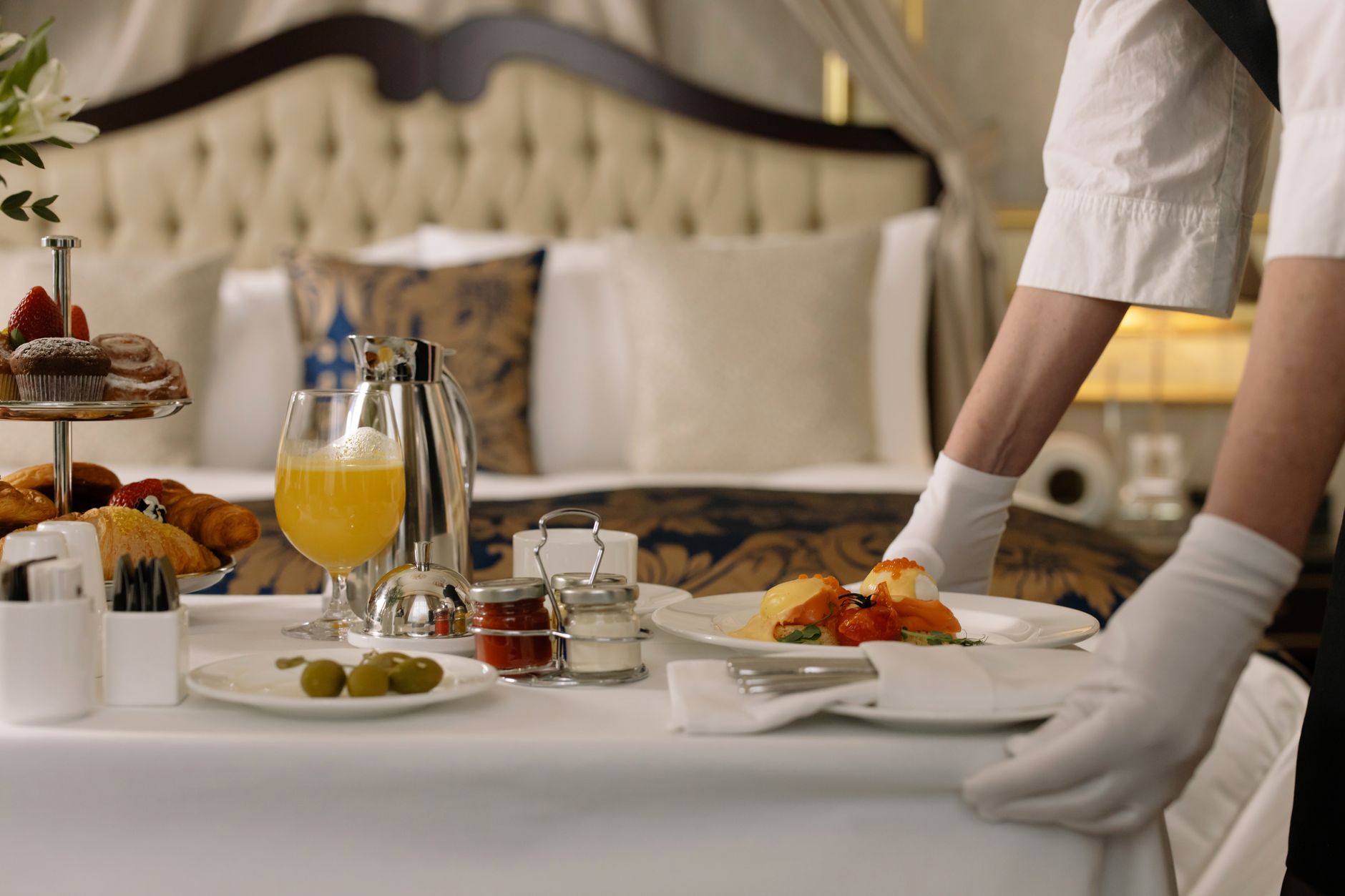Elegant room service breakfast with orange juice and pastries in a hotel room.