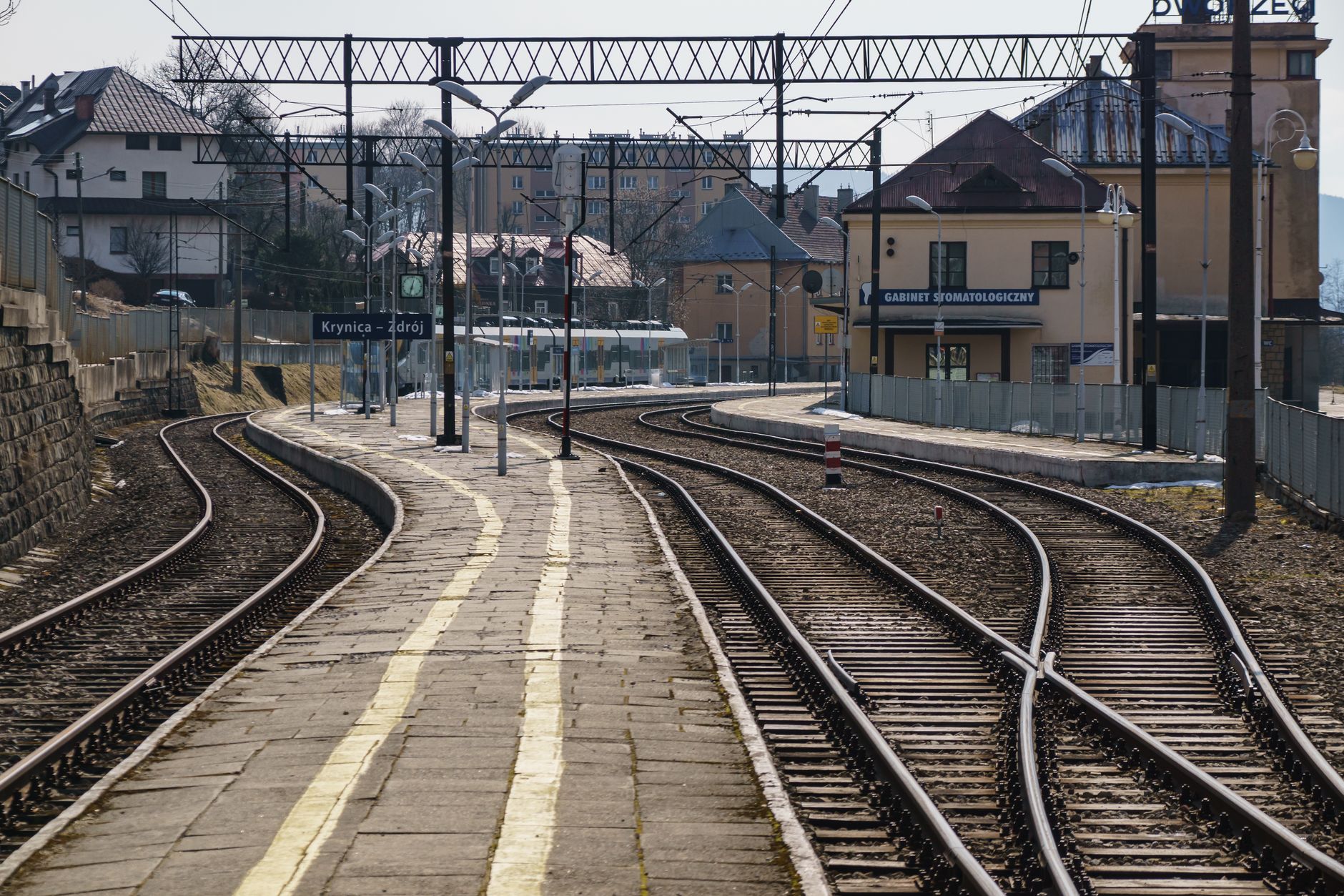 Curved railway tracks at Krynica-Zdrój station with scenic backdrop.