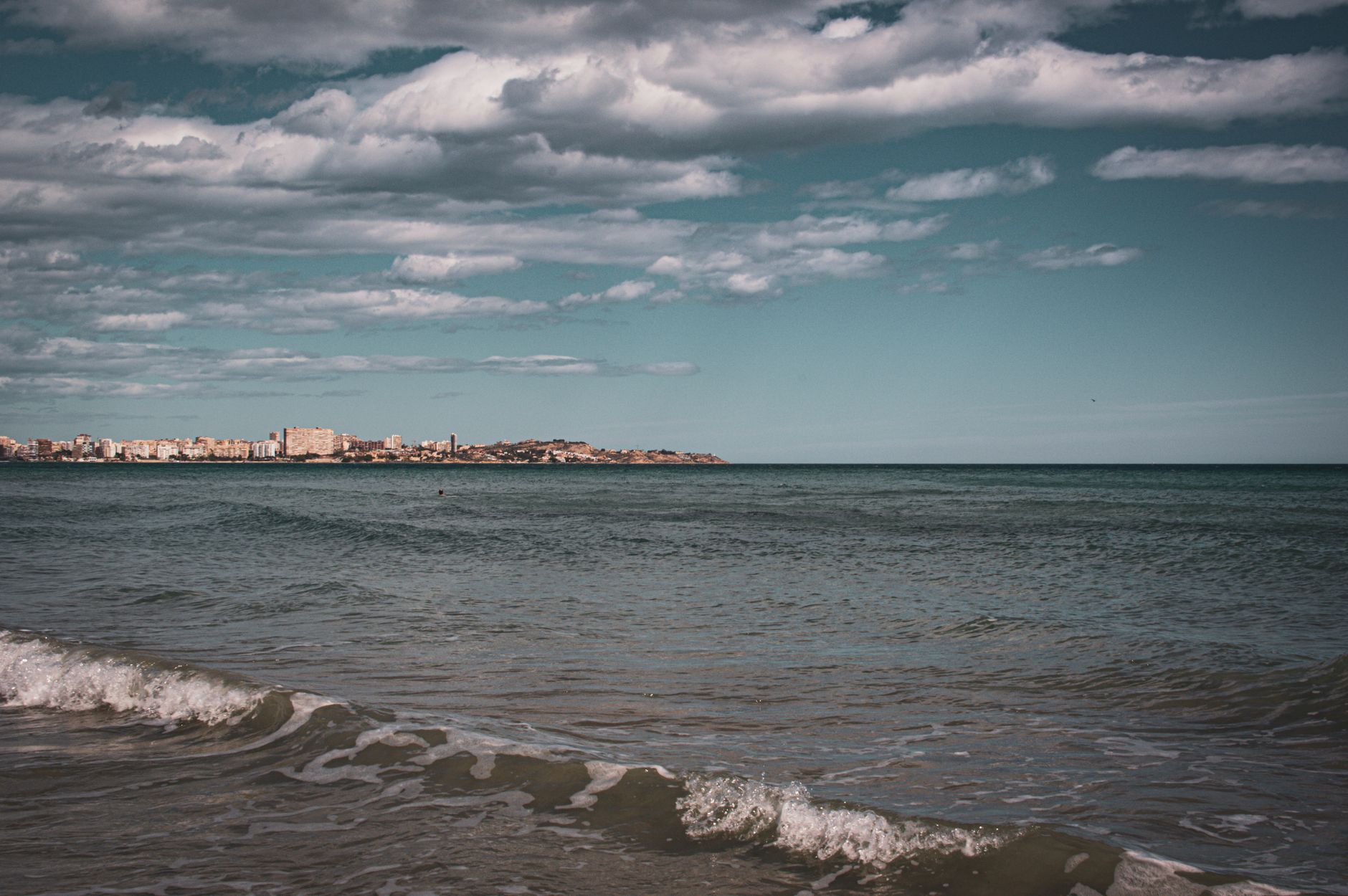 A picturesque view of Alicante's coastline under a dramatic cloudy sky, capturing the essence of coastal Spain.