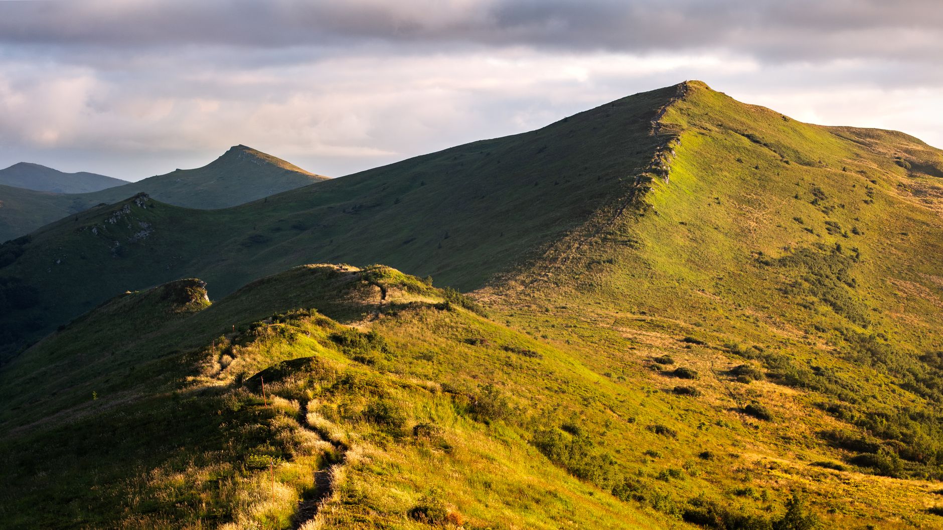 Bieszczady mountain range with green valleys and trails in early morning light, perfect for hiking adventures.