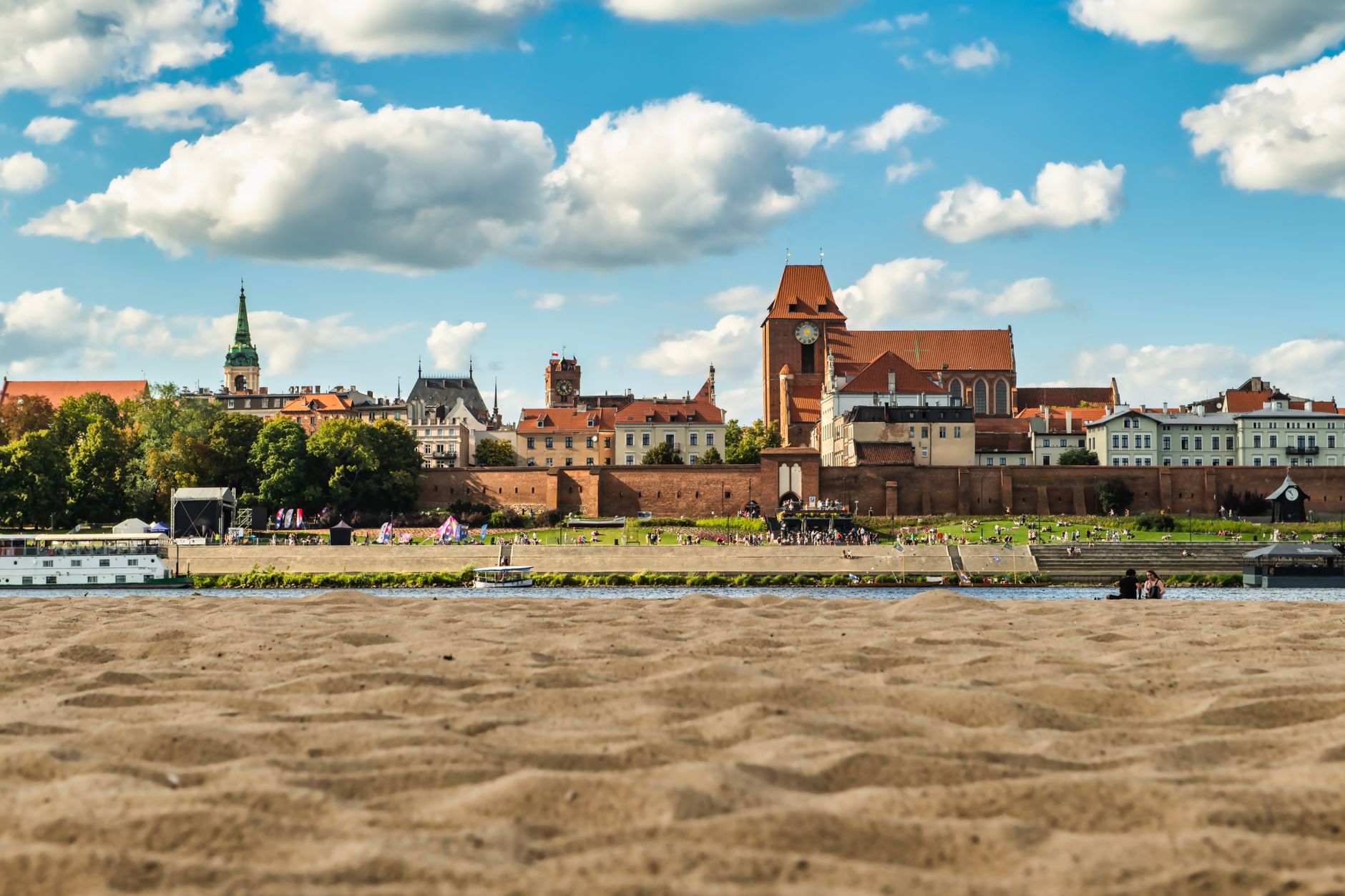 A picturesque view of Toruń's cityscape with architectural landmarks under a vibrant blue sky.