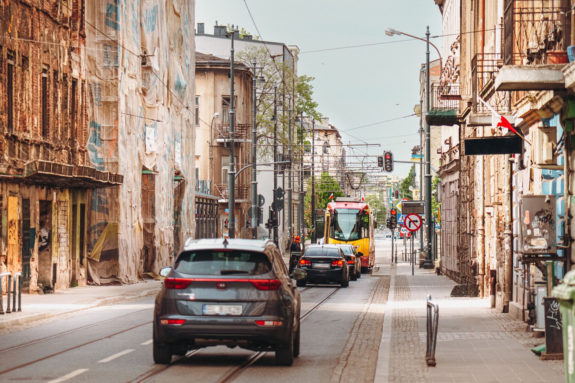 A vibrant urban scene in Łódź, Poland, featuring a tram and vehicles amidst historic architecture.