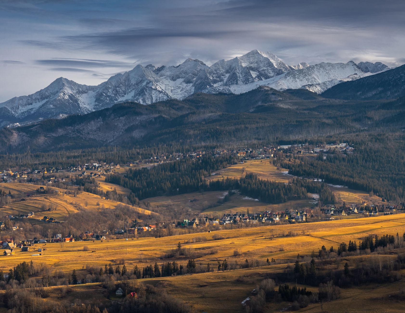 Stunning aerial view of Zakopane in autumn, with the snow-capped Tatra Mountains in the background.