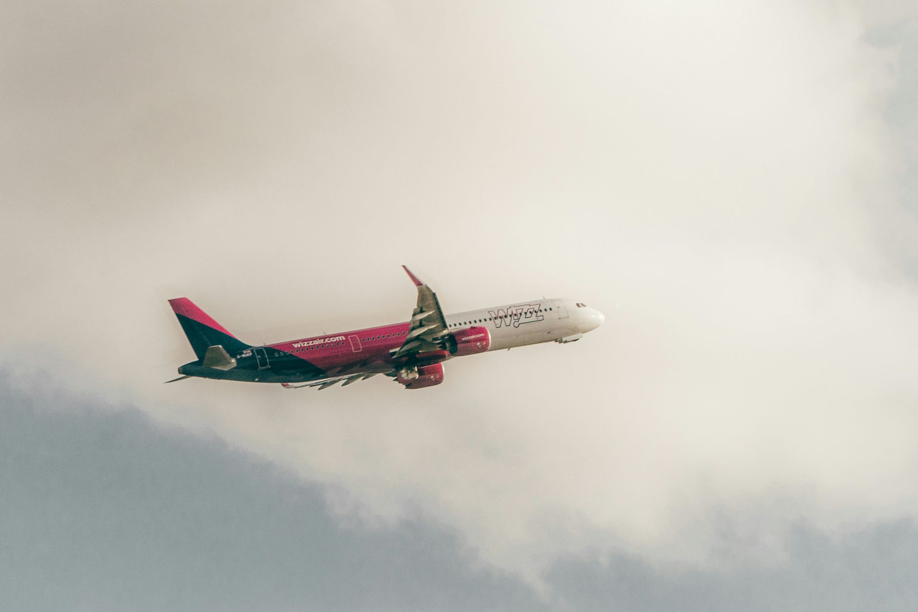A Wizz Air airplane in flight against a cloudy sky, capturing the essence of air travel.