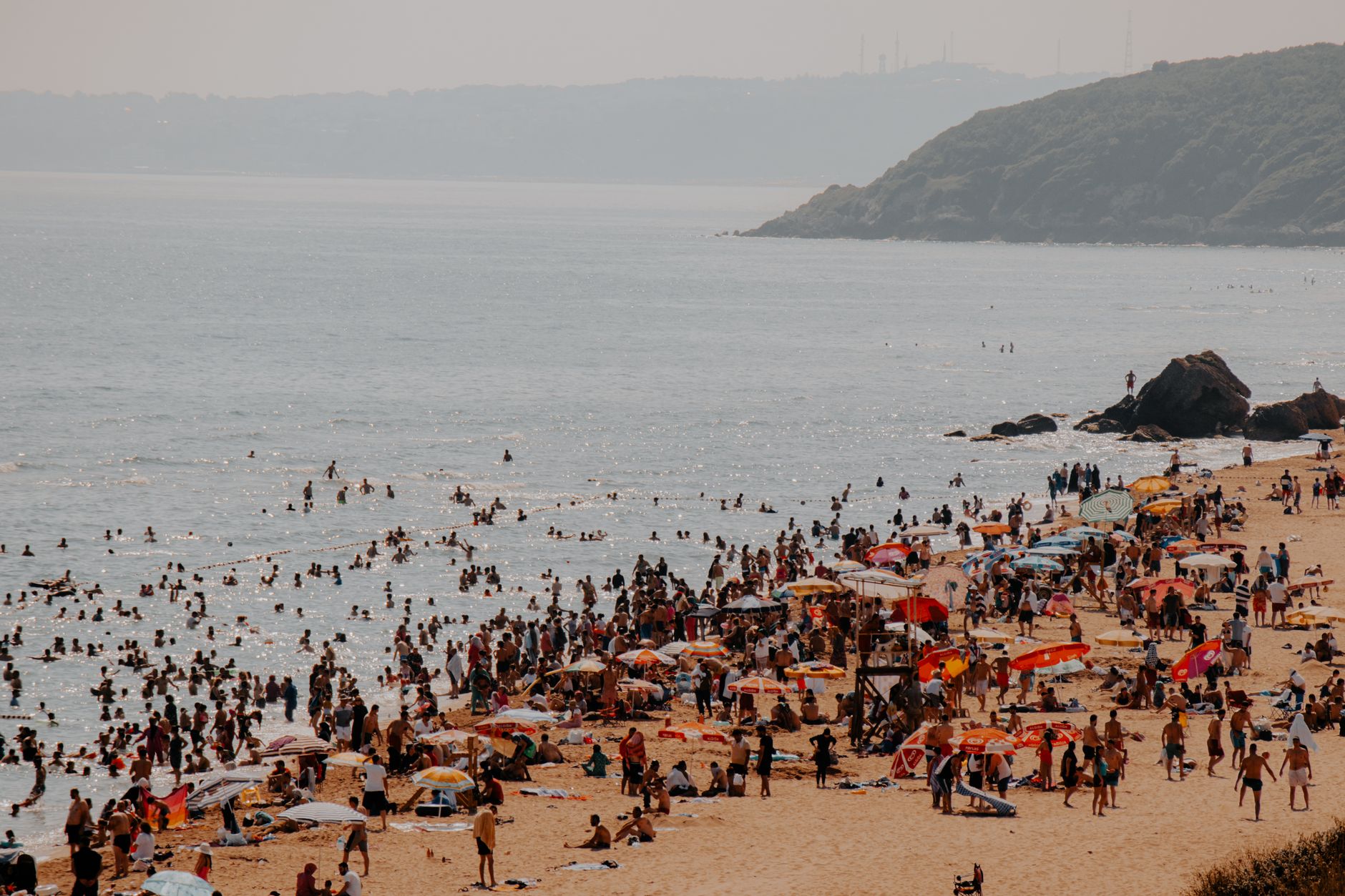 Crowded summer beach at Kilyos, İstanbul with swimmers and umbrellas.