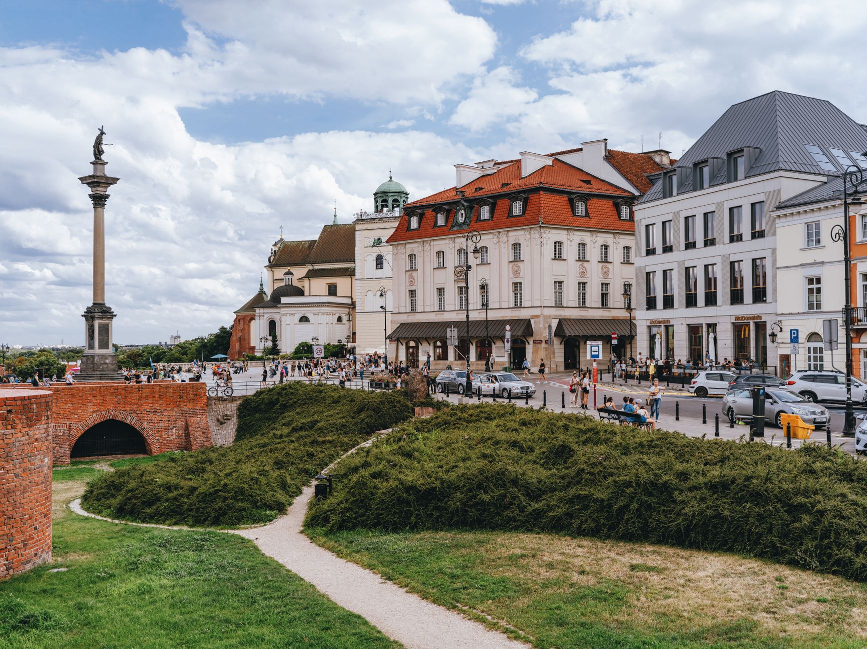 Picturesque scene of Warsaw's Old Town with historical buildings and Sigismund's Column under a bright sky.