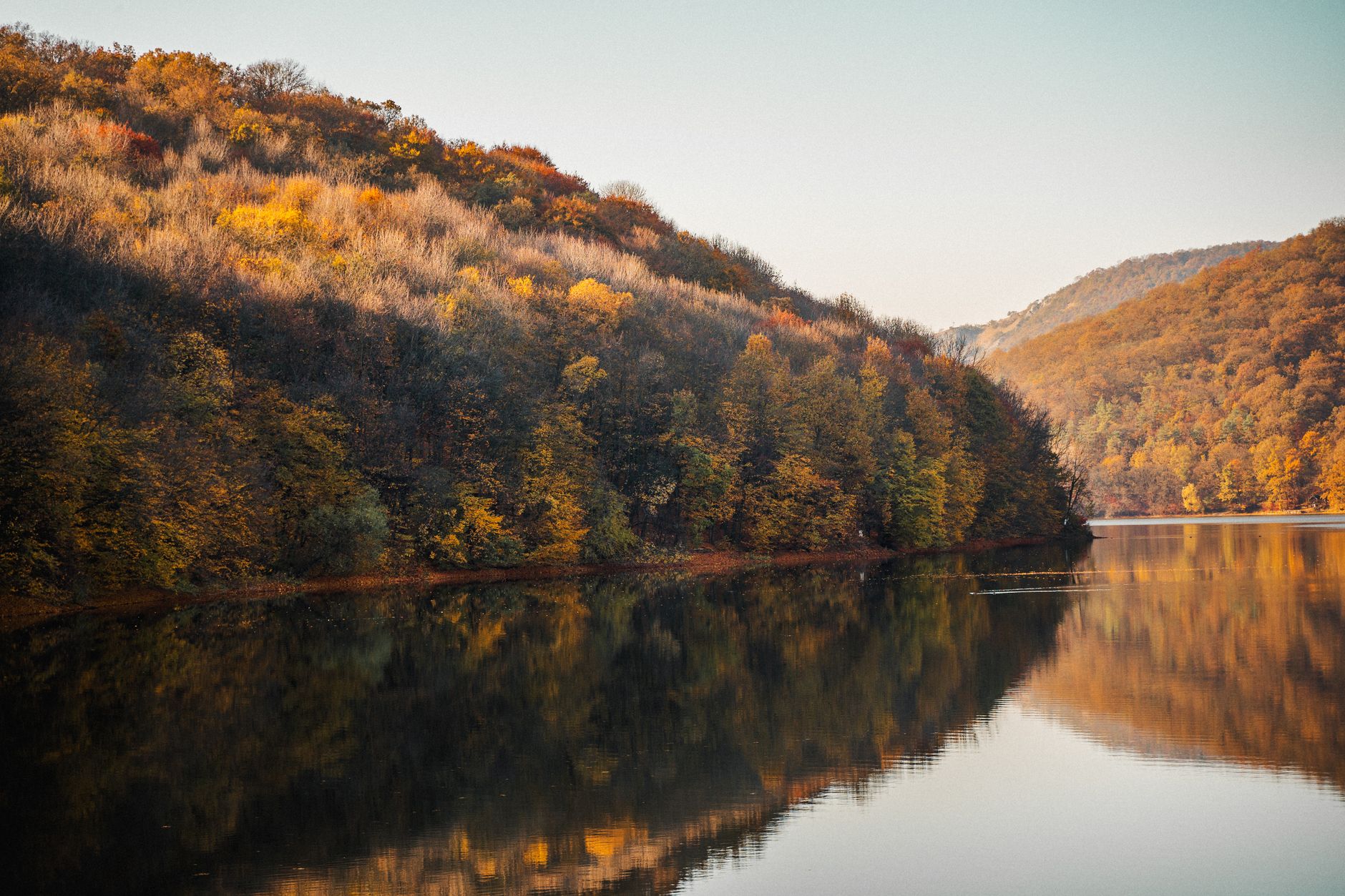 Stunning autumn landscape with a tranquil lake reflecting colorful forested hills.