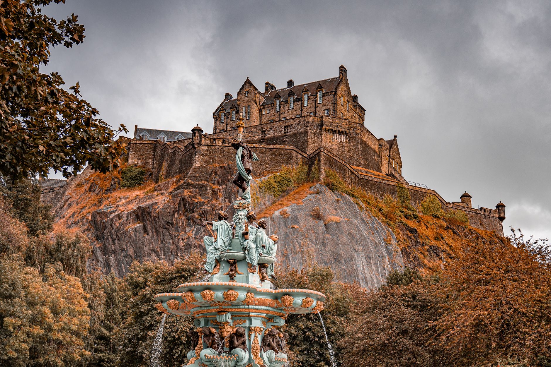 A majestic shot of Edinburgh Castle atop Castle Rock, surrounded by autumn foliage.
