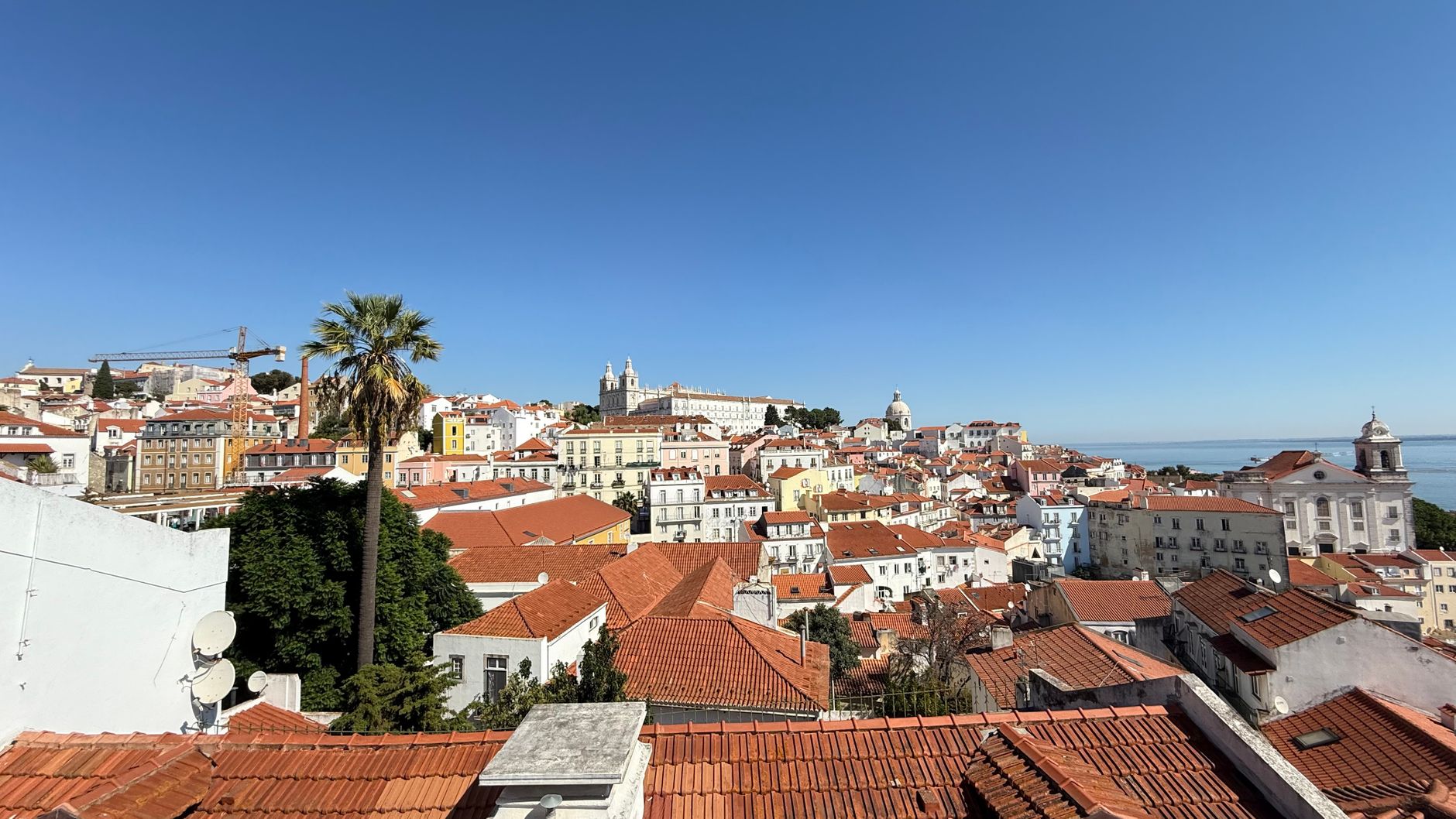 Experience the vibrant landscape of Lisbon with its iconic red tiled rooftops under a clear blue sky.