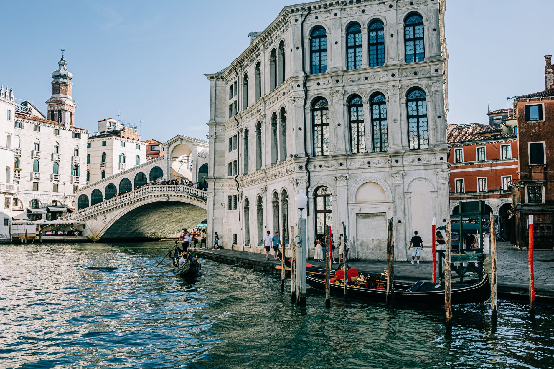 Scenic view of Rialto Bridge over the Grand Canal in Venice with gondolas and historic architecture.