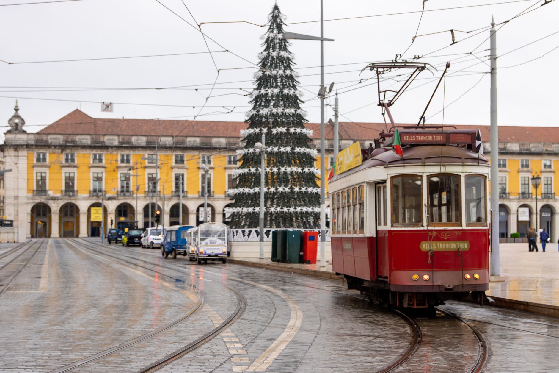 Iconic Lisbon tram near decorated Christmas tree in Praça do Comércio, Portugal.
