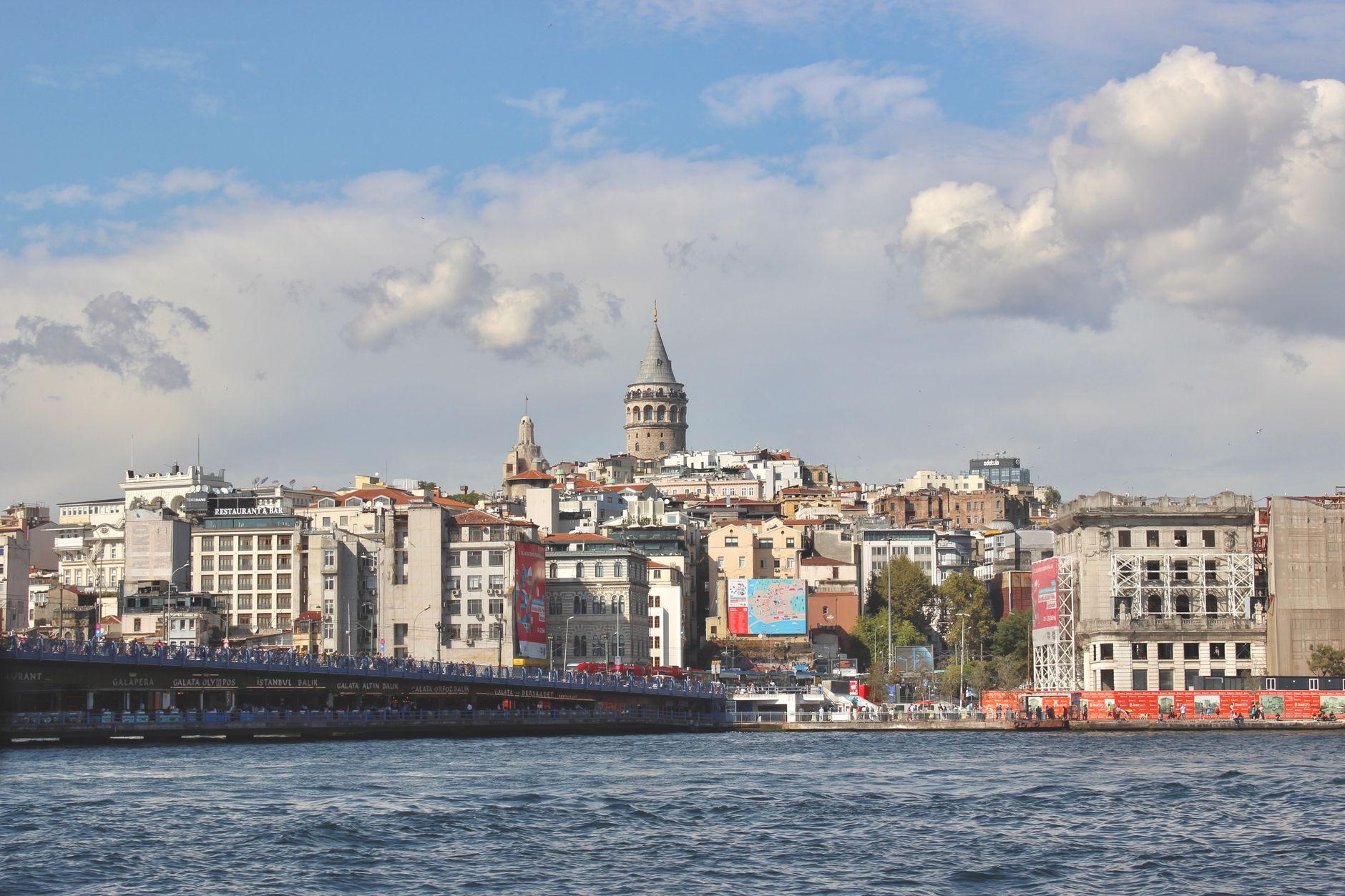 Beautiful view of Galata Tower and Istanbul's cityscape by the Bosphorus under a clear sky.